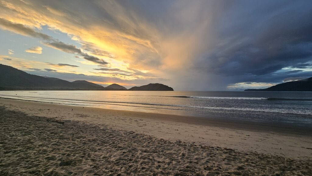 Praia do Perequê-Açu ao entardecer, com mar calmo e montanhas ao fundo, Ubatuba