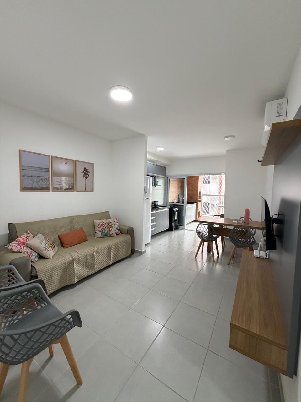 Sala de estar mobiliada com sofá e sala de jantar integrada no Residencial Alpha Prime
