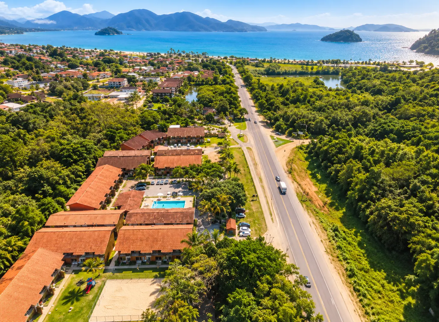 Vista aérea do condomínio em Maranduba, Ubatuba, com piscina, área verde e o mar ao fundo