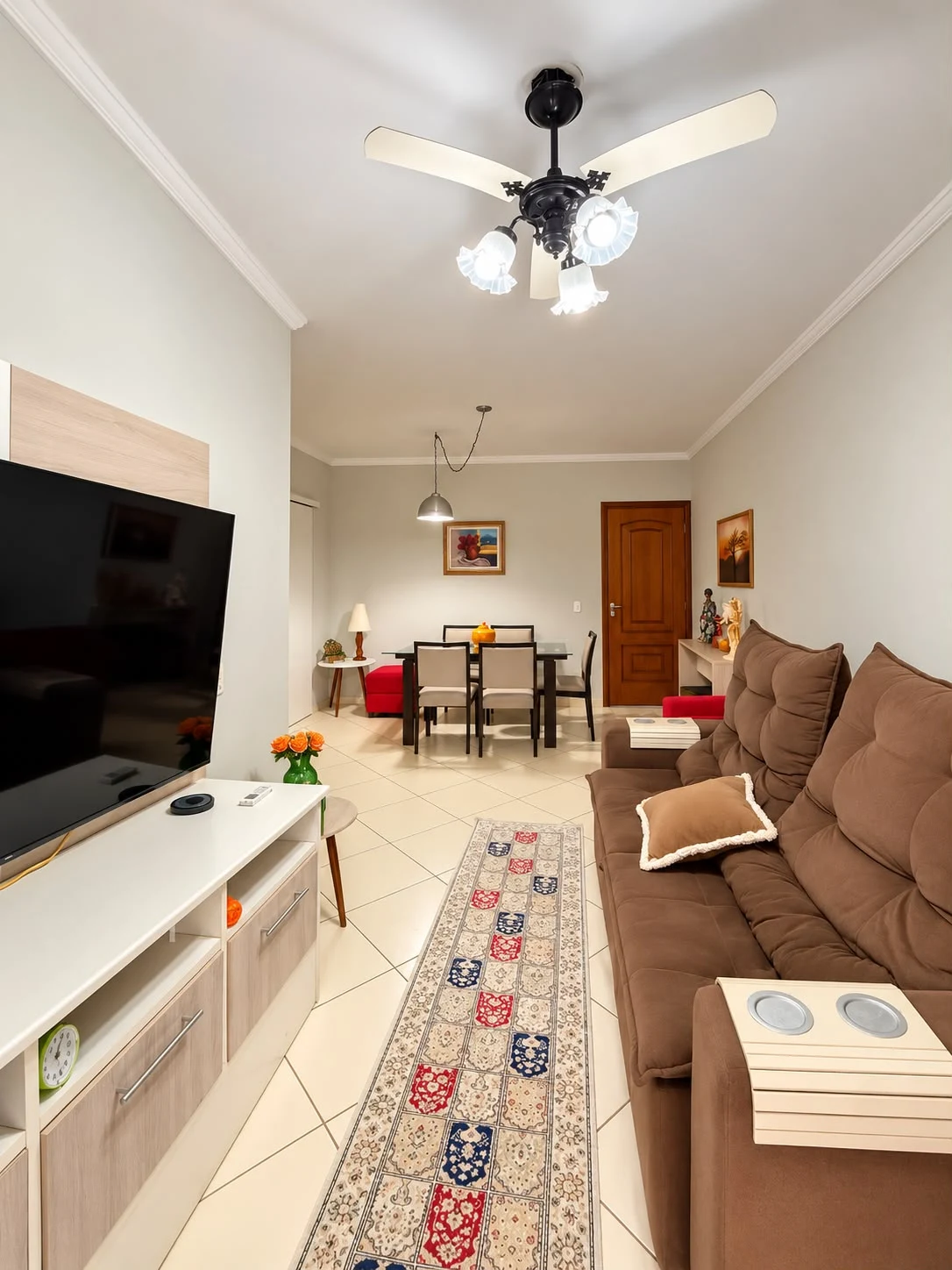 Sala de estar com sofá, televisão e ventilador de teto, apartamento na Rua Professora Licínia, Itaguá