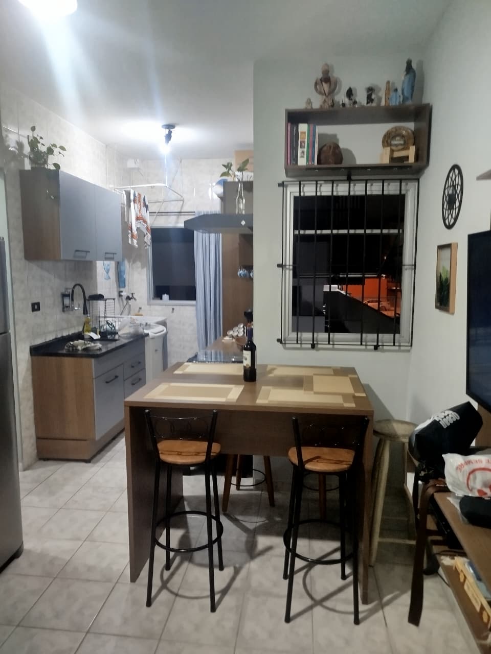 Mesa de jantar alta com banquetas, integrada à cozinha do apartamento em Itaguá