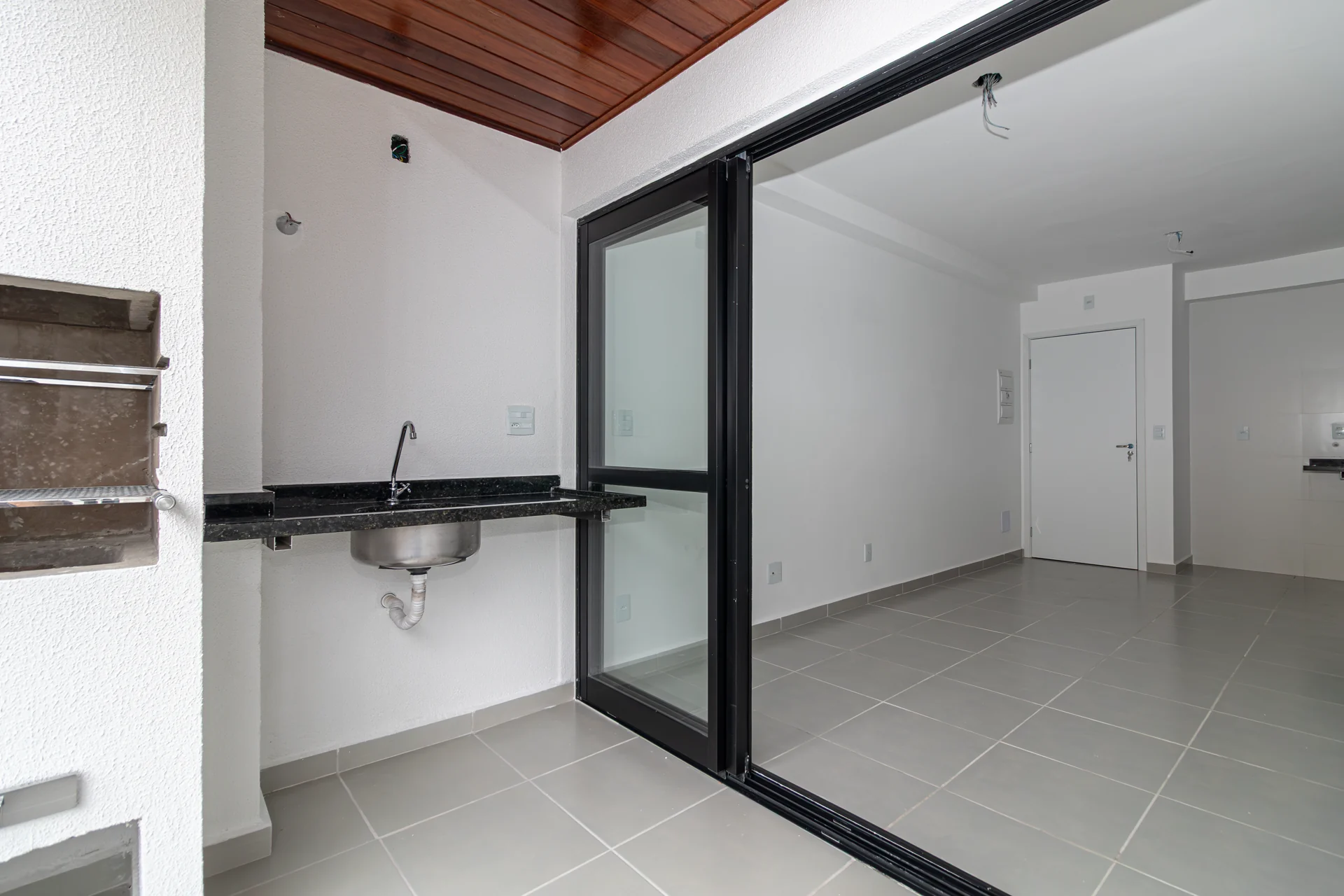 Varanda gourmet integrada à sala por porta de correr ampla, apartamento novo no Alpha Haus